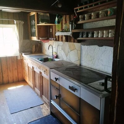 Kitchen of the Alm with a sink, wooden cabinets, and a wood-burning oven.