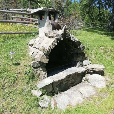 The stone barbecue grill in the garden area of the Alm, ideal for outdoor meals.