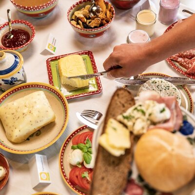 The farm house provides a breakfast spread with various jams, bread, butter, cheeses, and cold cuts.