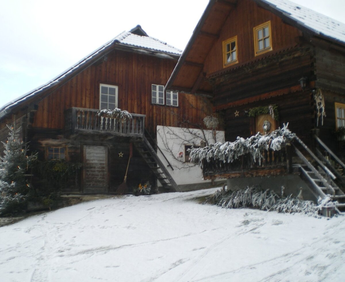 The Farm House exterior, featuring traditional wooden buildings with balconies, surrounded by a snow-covered landscape.
