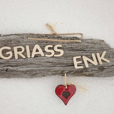 Guests are welcomed to the Farm House by a wooden sign featuring the local greeting "GRIASS ENK" and a red heart.