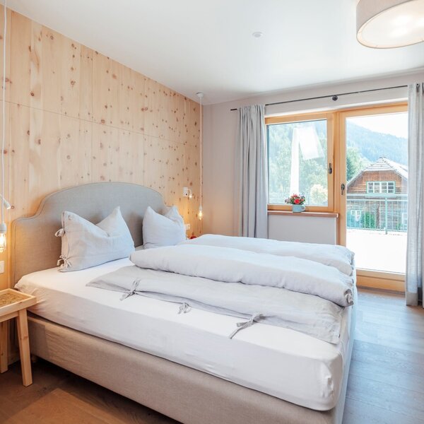 Double bedroom in the Farm House featuring wooden paneling, parquet flooring, a furnished balcony, and satellite TV. Double bedroom in the Farm House featuring wooden paneling, parquet flooring, a furnished balcony, and satellite TV.