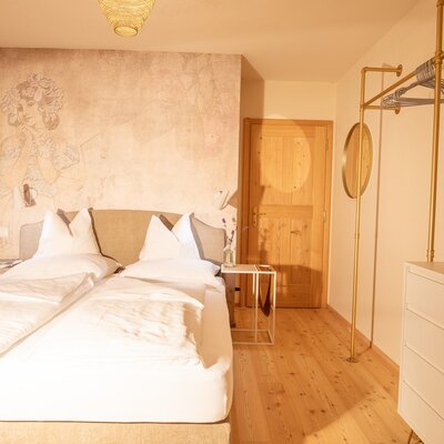 Bedroom in the Ferienhaus with a double bed, wall mural, wooden floor, bedside table, and open wardrobe.