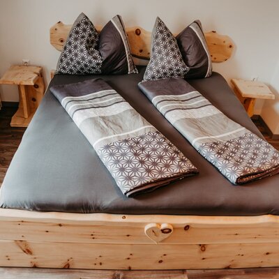 Double bedroom in the Farm House, featuring a wooden bed frame with dark grey bedding, patterned pillows, and two wooden bedside tables.