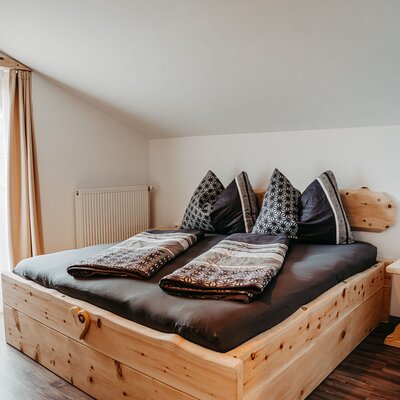 Bedroom in the farm house with a wooden double bed, dark bedding, a radiator, and a slanted ceiling.