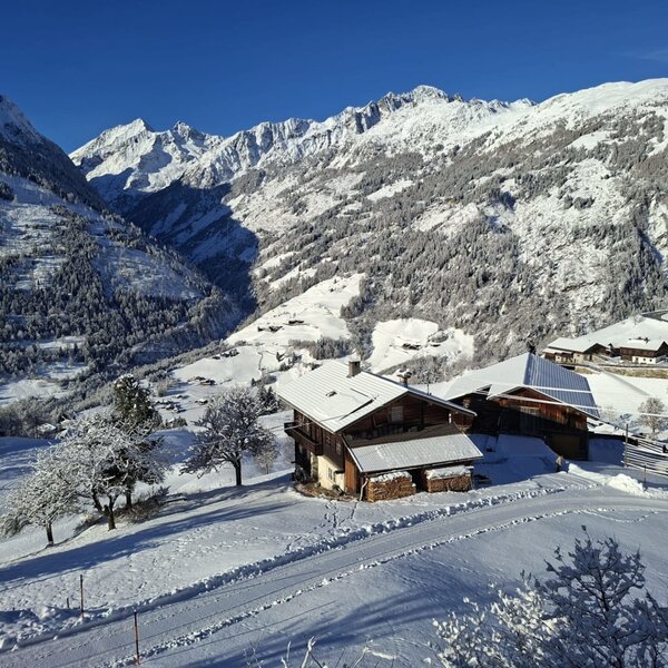 The farmhouse in a snowy mountain landscape with views of the surrounding mountains.