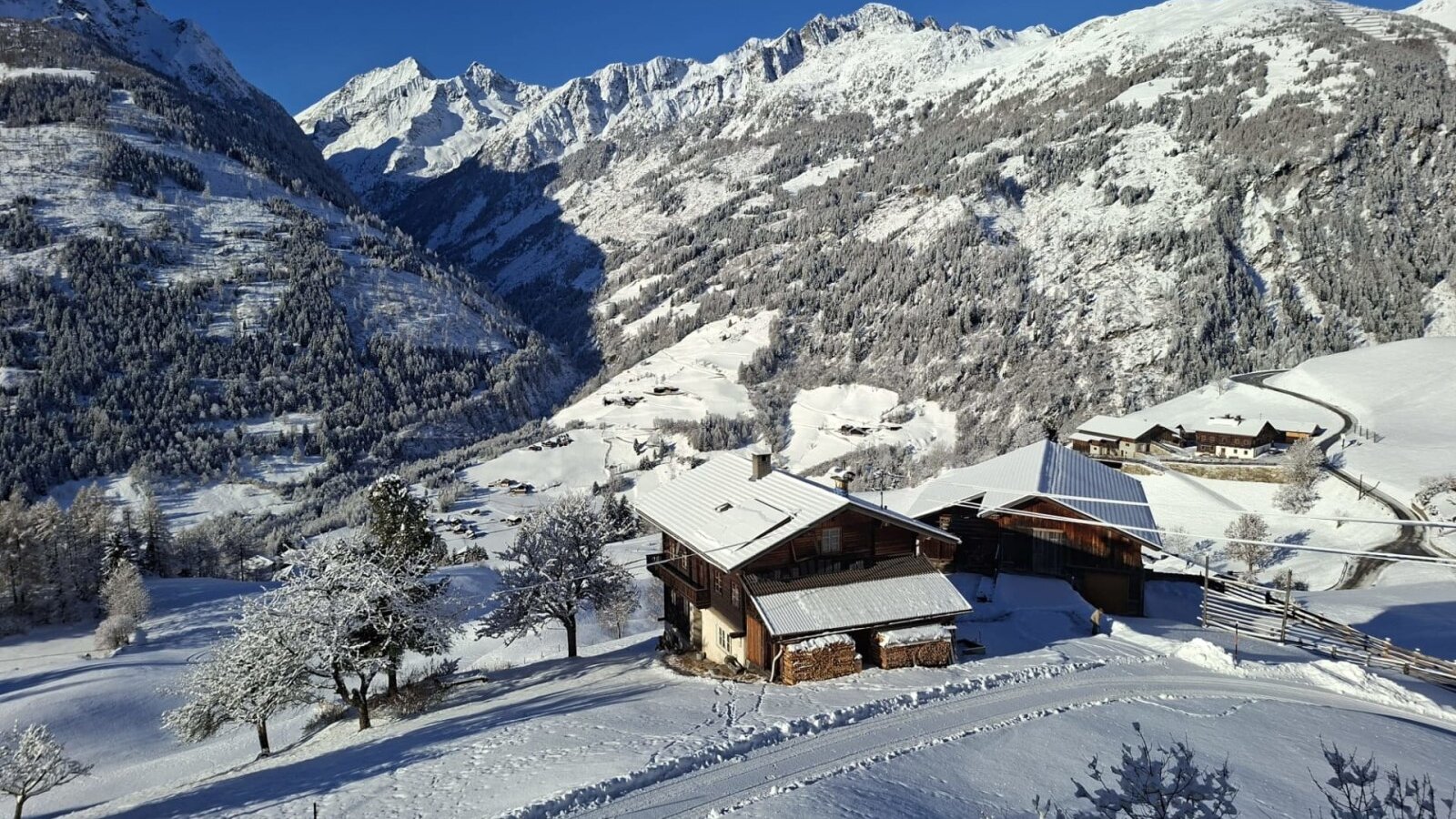 The farmhouse in a snowy mountain landscape with views of the surrounding mountains.