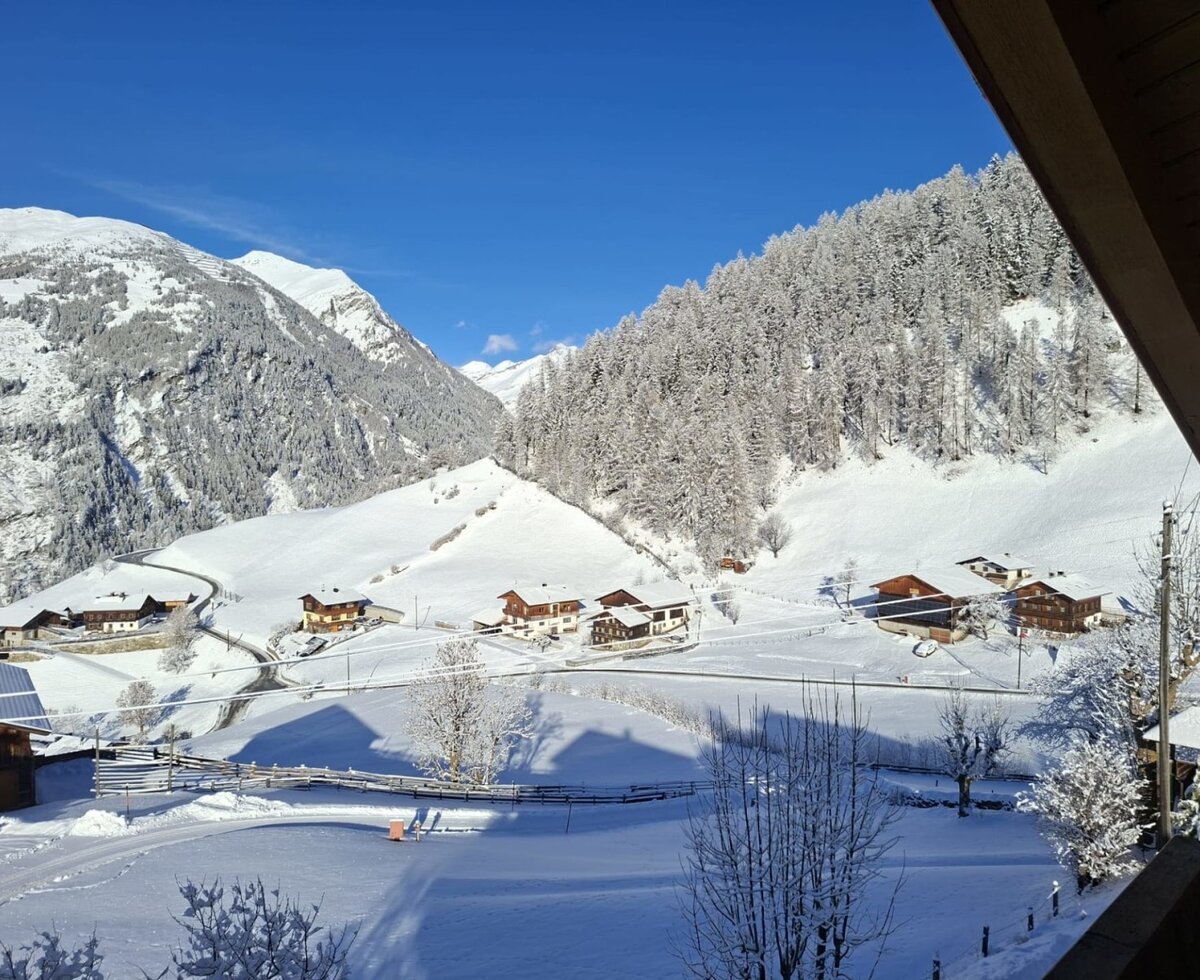 View from the farmhouse of the snowy mountain landscape with houses in the valley.