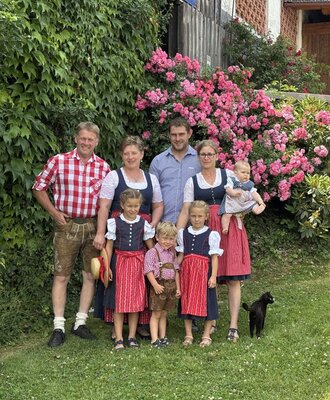 The host family of the farmhouse in traditional attire with children in the blooming garden.