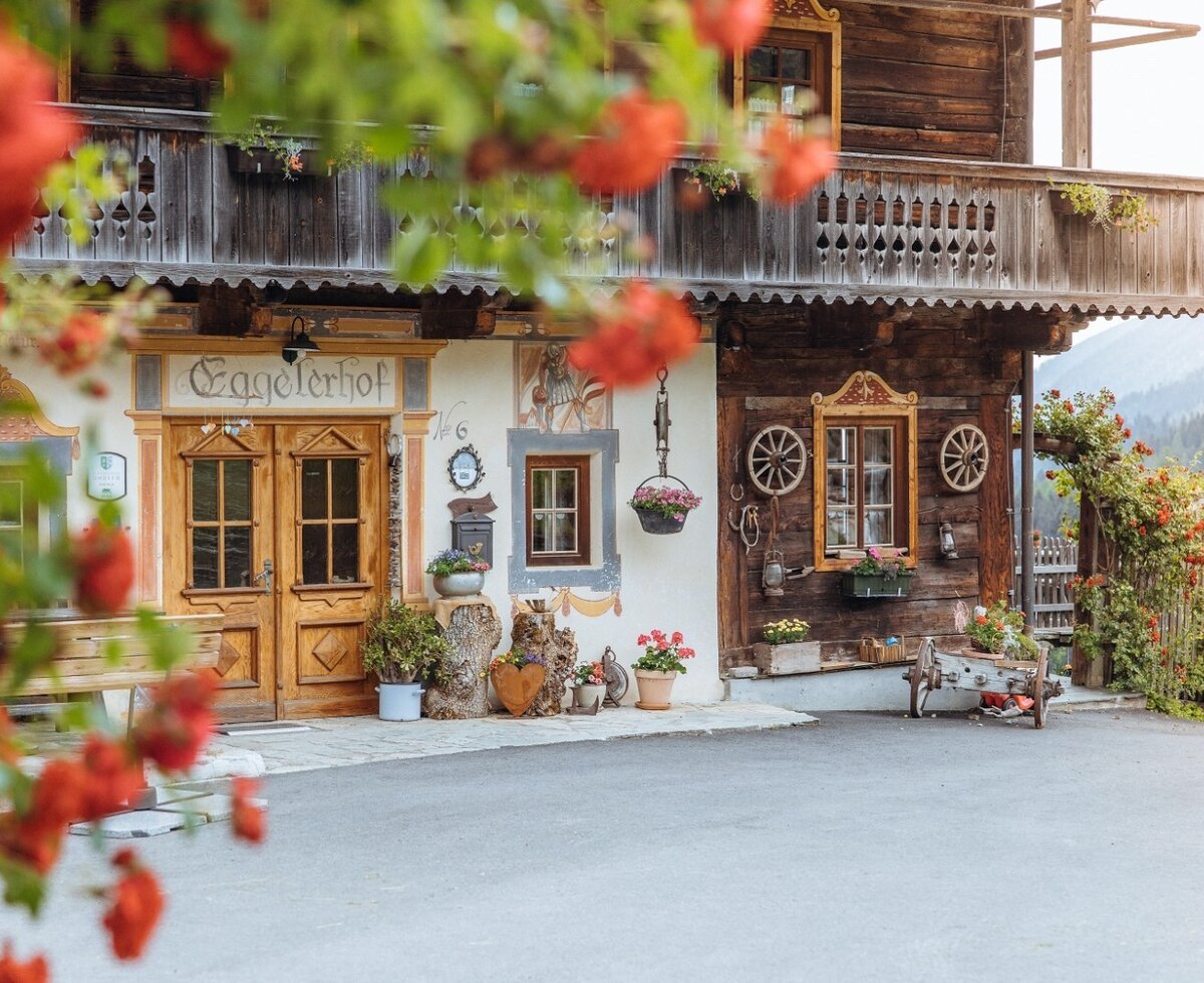 Exterior view of the "Eggelerhof" farmhouse, featuring a wooden balcony, traditional wooden doors, and a painted facade.