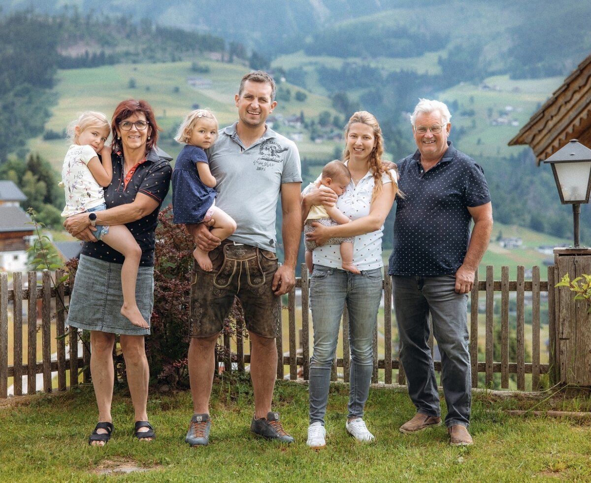 The host family of the farmhouse in front of the mountain landscape.