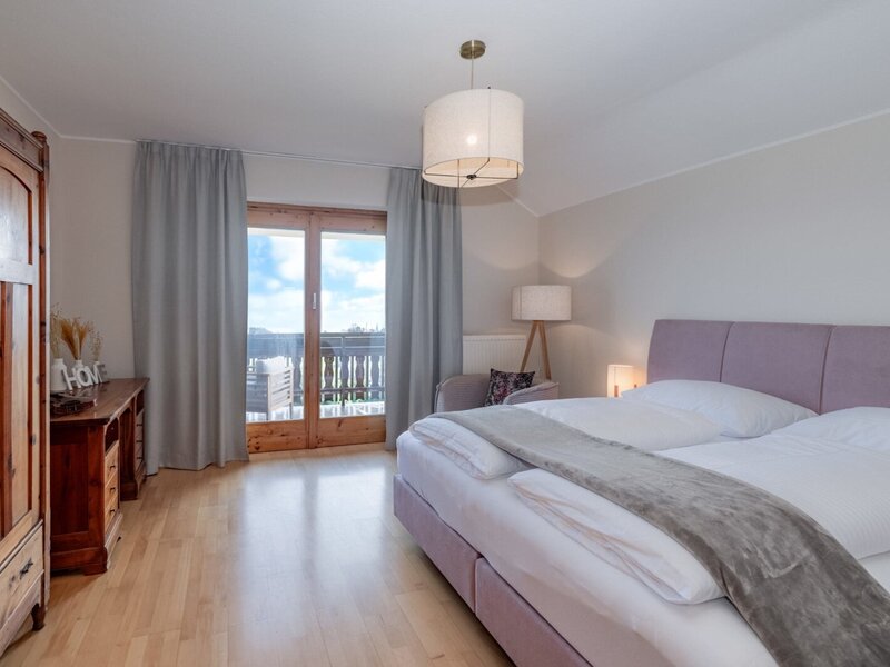 Bedroom in the farmhouse with a double bed, wooden wardrobe, and balcony access.