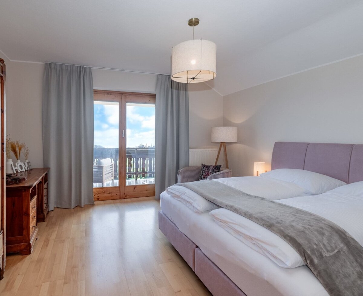 Bedroom in the farmhouse with a double bed, wooden wardrobe, and balcony access.