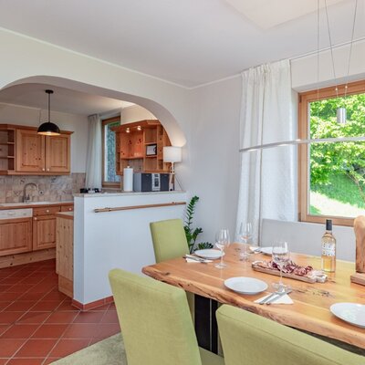 The large dining table in the farmhouse, set for a meal, with a view of the fully equipped kitchen.