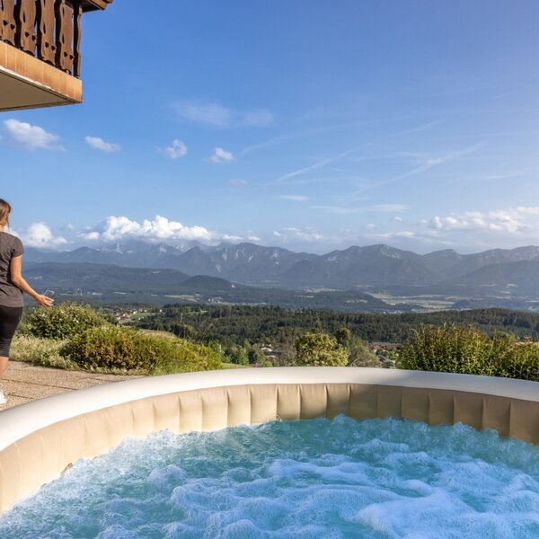 The hot tub and outdoor shower on the farmhouse terrace, offering a wide view over the mountains and valley.
