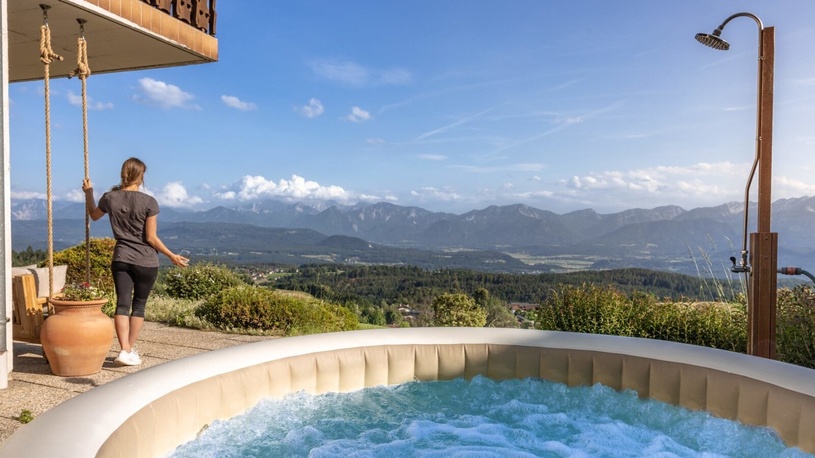 The hot tub and outdoor shower on the farmhouse terrace, offering a wide view over the mountains and valley.