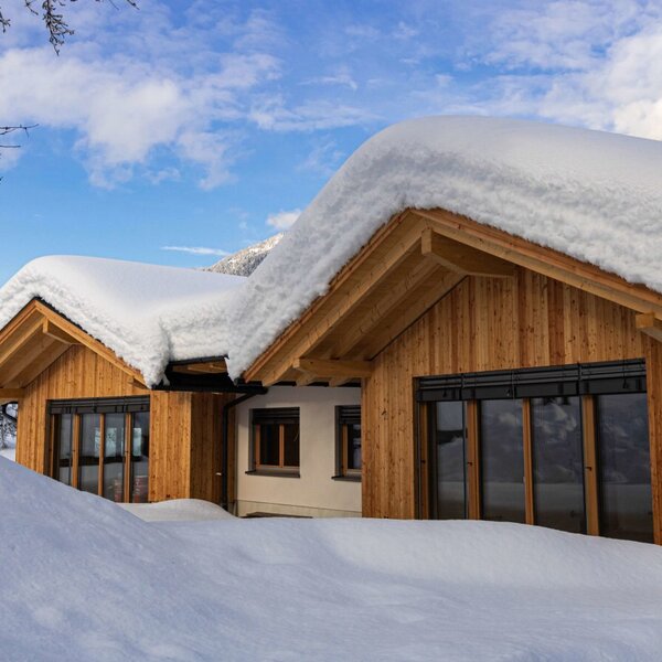The Farm House exterior in winter, featuring wooden paneling, snow-covered roofs, and windows with blinds. The Farm House exterior in winter, featuring wooden paneling, snow-covered roofs, and windows with blinds.