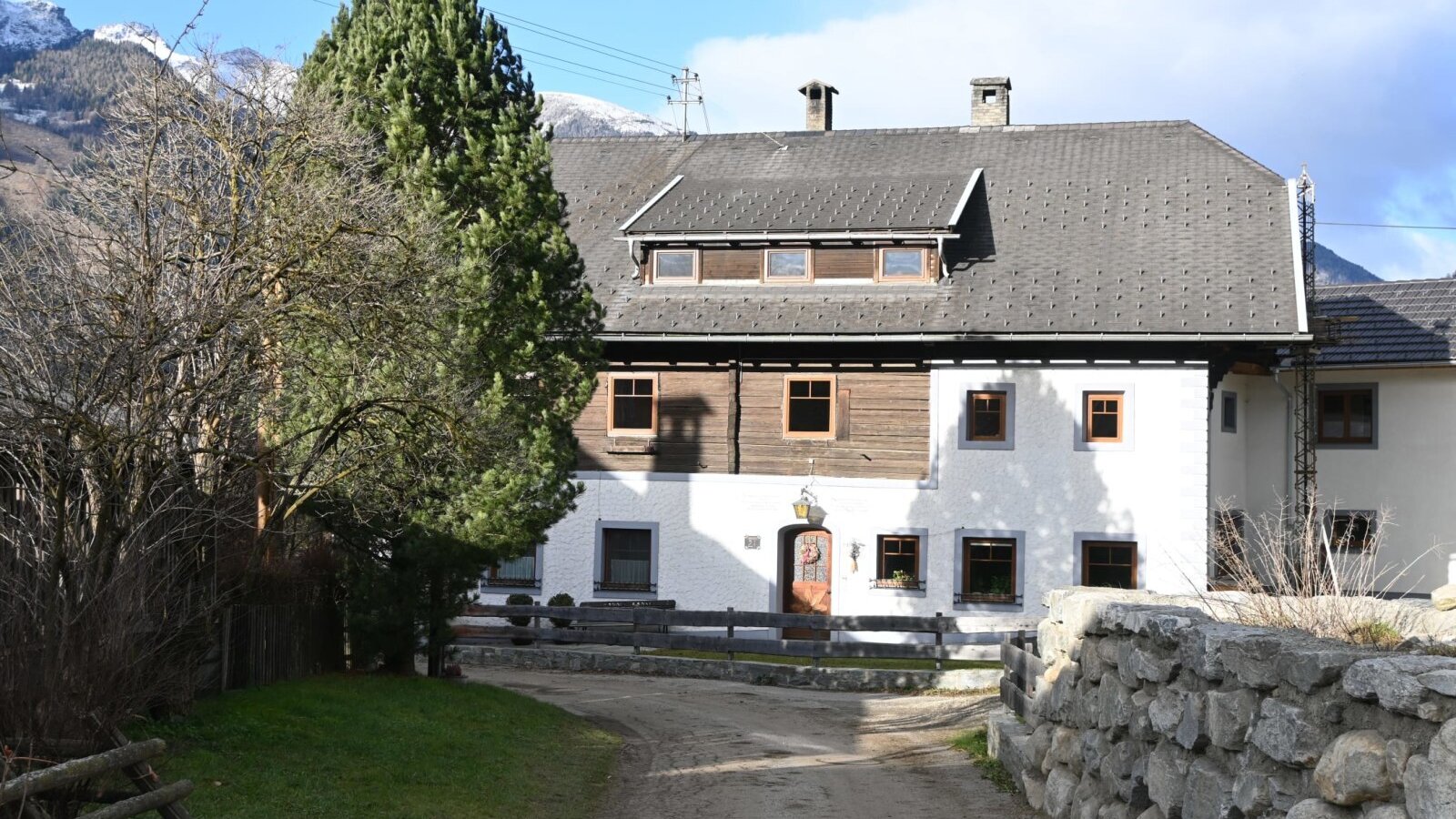 Exterior view of the Ferienwohnung with whitewashed walls, wooden cladding, and an access path.
