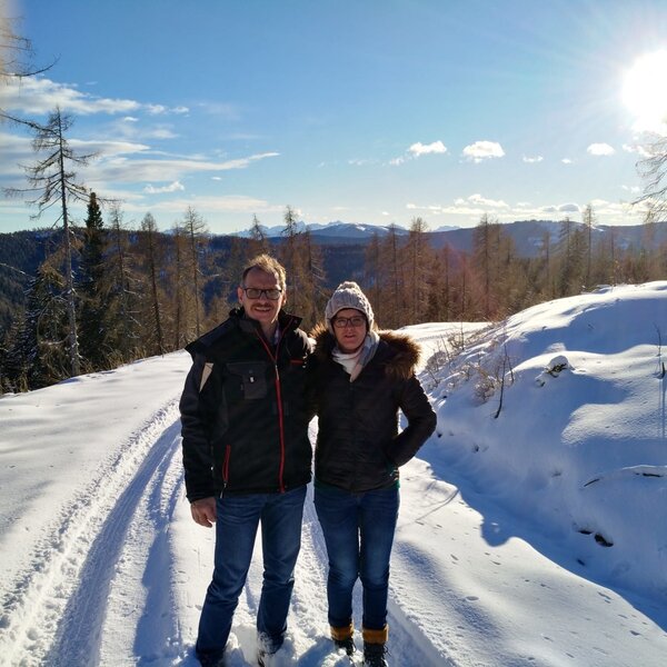 A snowy mountain path surrounded by trees and distant peaks, available for winter walks near the farmhouse.