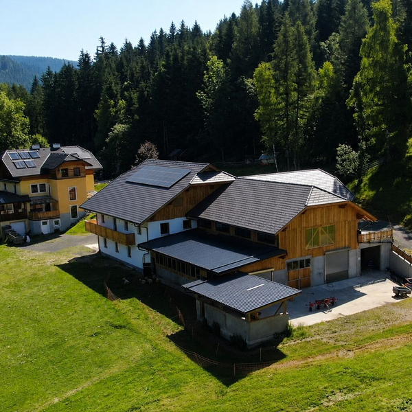 An idyllically situated farmhouse surrounded by lush green meadows and dense forests.