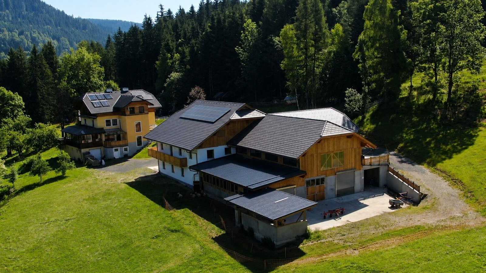 An idyllically situated farmhouse surrounded by lush green meadows and dense forests.