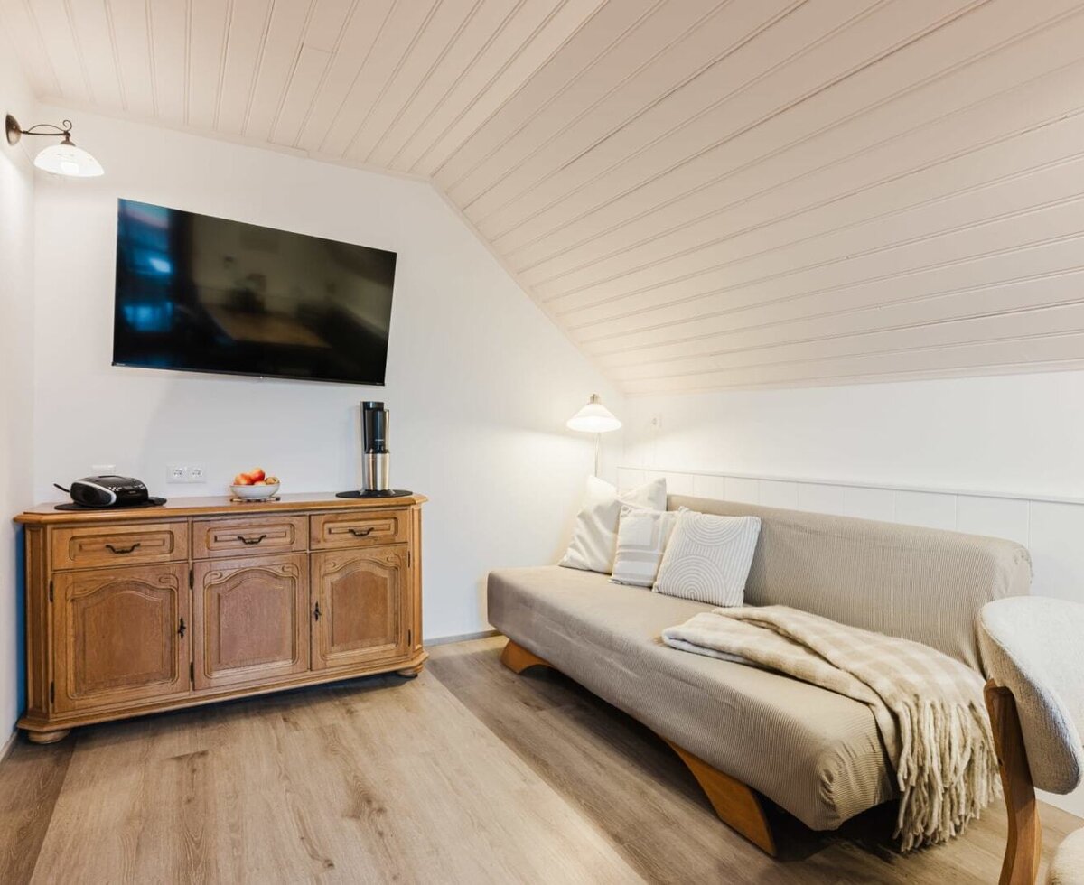 Living area in the farmhouse with a large flat-screen TV, rustic wooden sideboard, and sofa.