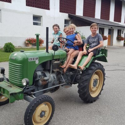 Children enjoying a ride on a green tractor at the Farm House.