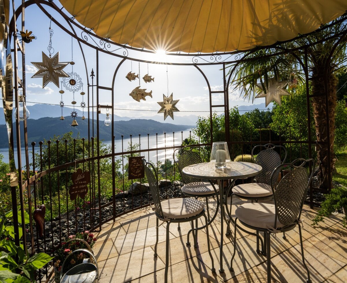 Outdoor seating area under a gazebo at the farmhouse, offering views of Lake Millstatt and the mountains.