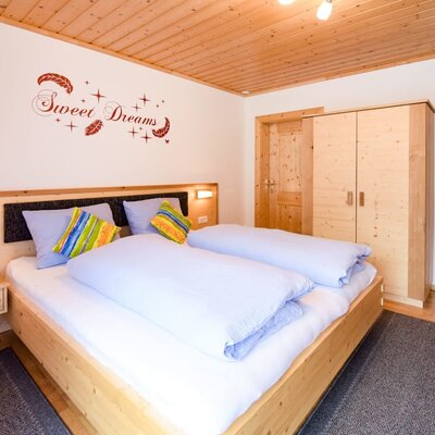 A bright bedroom in the farmhouse apartment featuring a cozy double bed and light wood furniture.
