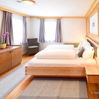 A bright and welcoming bedroom in the farmhouse apartment, featuring a cozy wooden double bed and plenty of natural light.