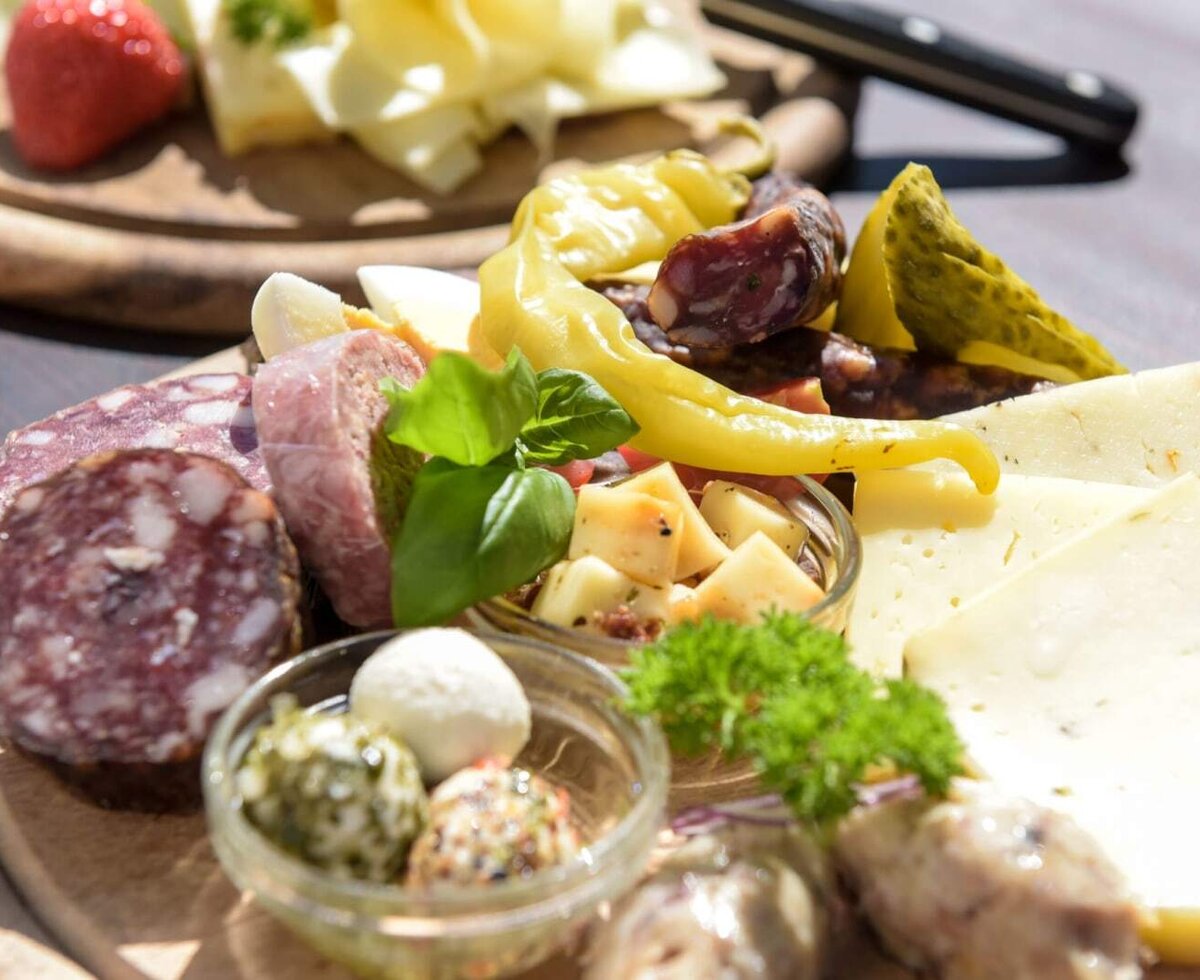 A hearty snack platter from the farmhouse, featuring fine cheeses, cured meats, and fresh herbs.