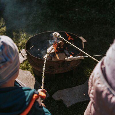 Guests roasting stick bread over a campfire at the farmhouse.
