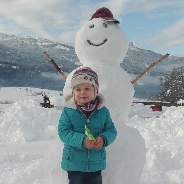 Guests can enjoy winter activities like building snowmen on the snowy grounds of the farmhouse.