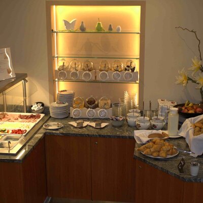 The breakfast buffet at the farmhouse offers a selection of cold cuts, vegetables, fruit, muesli, bread, and pastries.