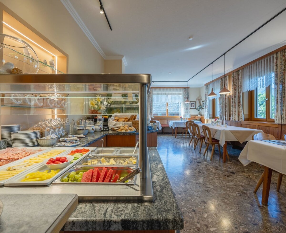 Breakfast buffet with cold cuts, cheese, fruit, and vegetables in the farmhouse dining area.