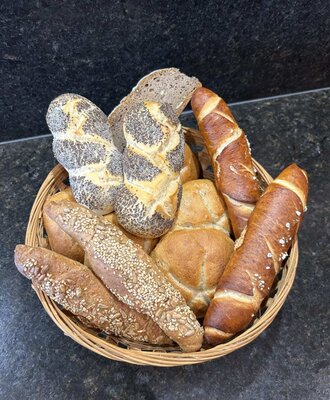 An inviting basket filled with fresh, warm bread rolls and pastries for a cozy breakfast in the apartment.