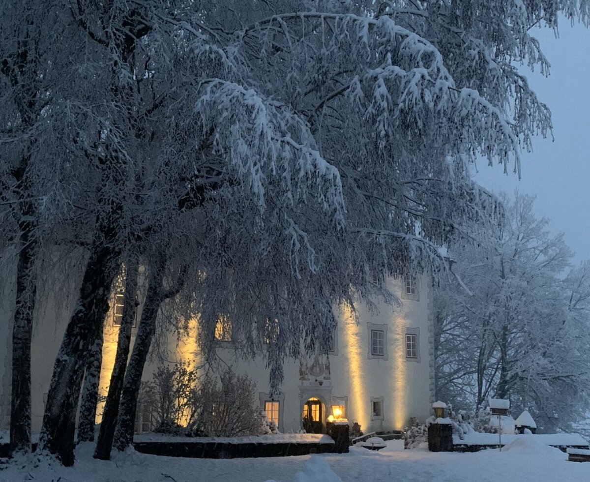 The apartment's historic building warmly lit amidst a snowy winter landscape.