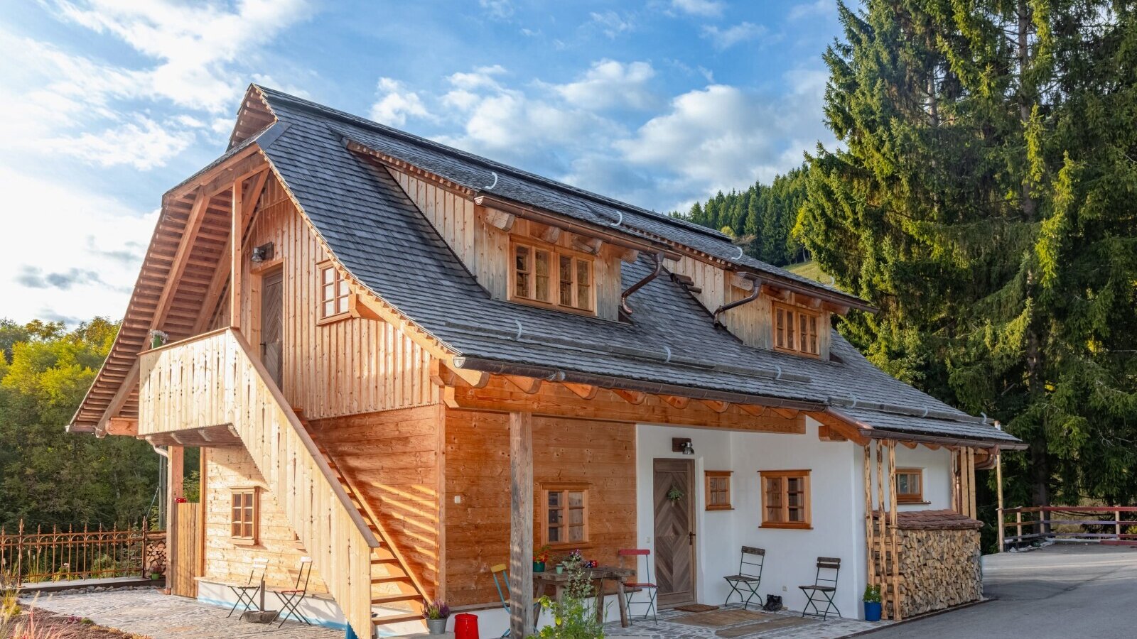 The holiday home featuring a wooden facade, white plastered walls, an exterior staircase, and a patio with seating.