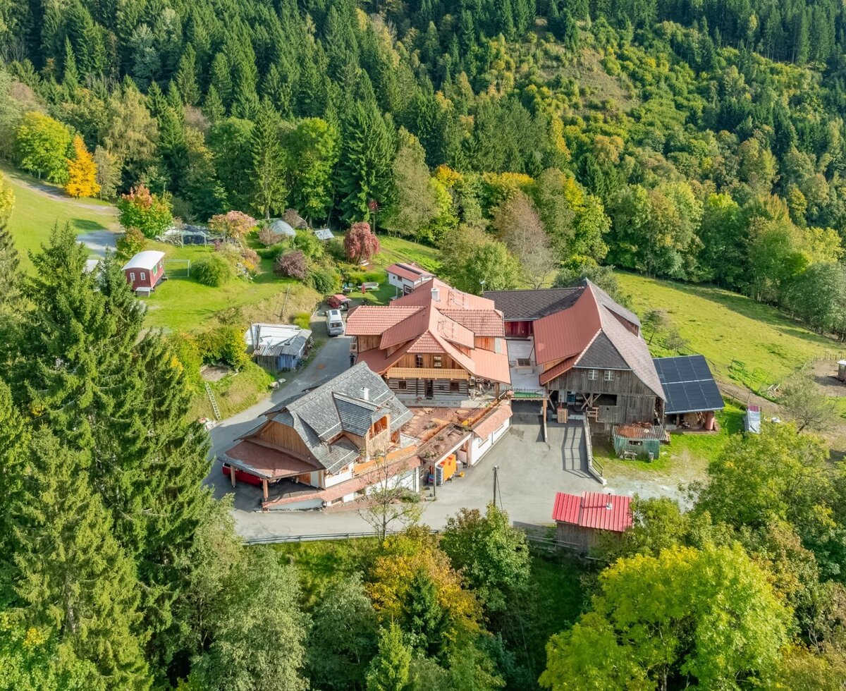 The holiday home property with multiple buildings, nestled amidst forests and green hills.