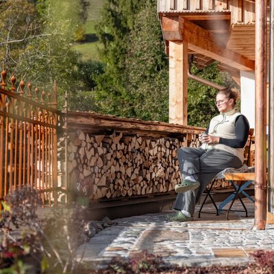 Paved patio at the holiday home with a stack of firewood and seating.