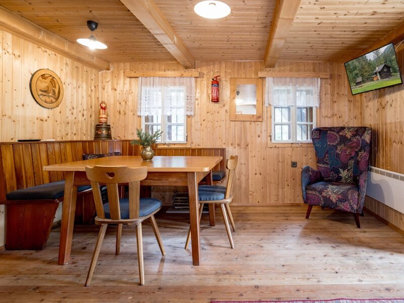 A cozy dining area in the Alm featuring rustic wood paneling, a traditional seating corner, and an inviting armchair.