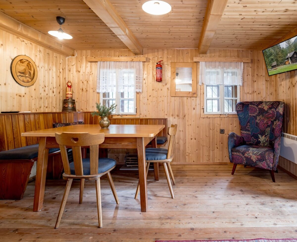 A cozy dining area in the Alm featuring rustic wood paneling, a traditional seating corner, and an inviting armchair.