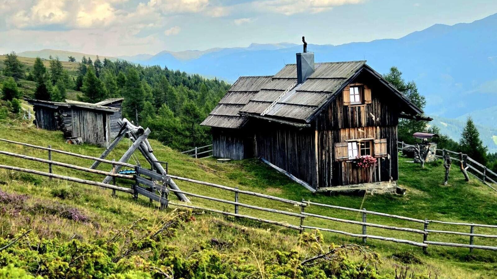 The rustic alm is nestled in an idyllic mountain landscape with vast meadows and sweeping views.
