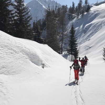 Guests ski touring through a snow-covered mountain valley, one of the winter activities offered by the farmhouse.