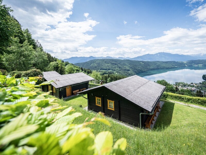 Several holiday homes on a hillside with a view of the lake and surrounding mountains.