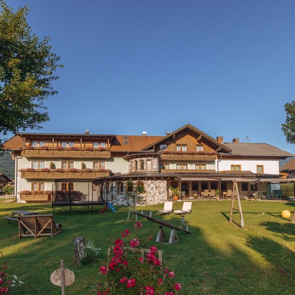 The Farm House exterior features a spacious garden with a children's play area including a trampoline, swings, and a seesaw, alongside an outdoor dining terrace.