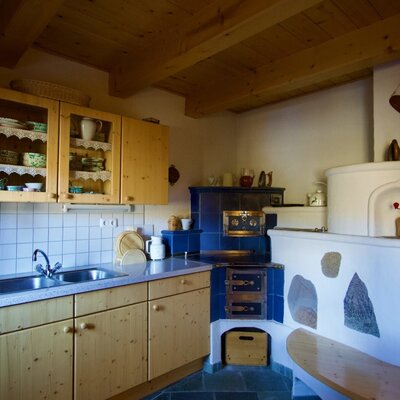 Kitchen in the Alm with a double sink, wooden cabinets, and a traditional tiled stove with a bench.