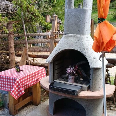 An inviting stone barbecue on the Alm's terrace, perfect for cozy outdoor dining surrounded by nature.