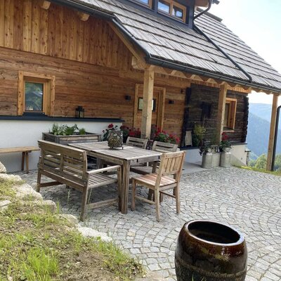 An inviting patio at the Alm with rustic wooden seating on a paved terrace.
