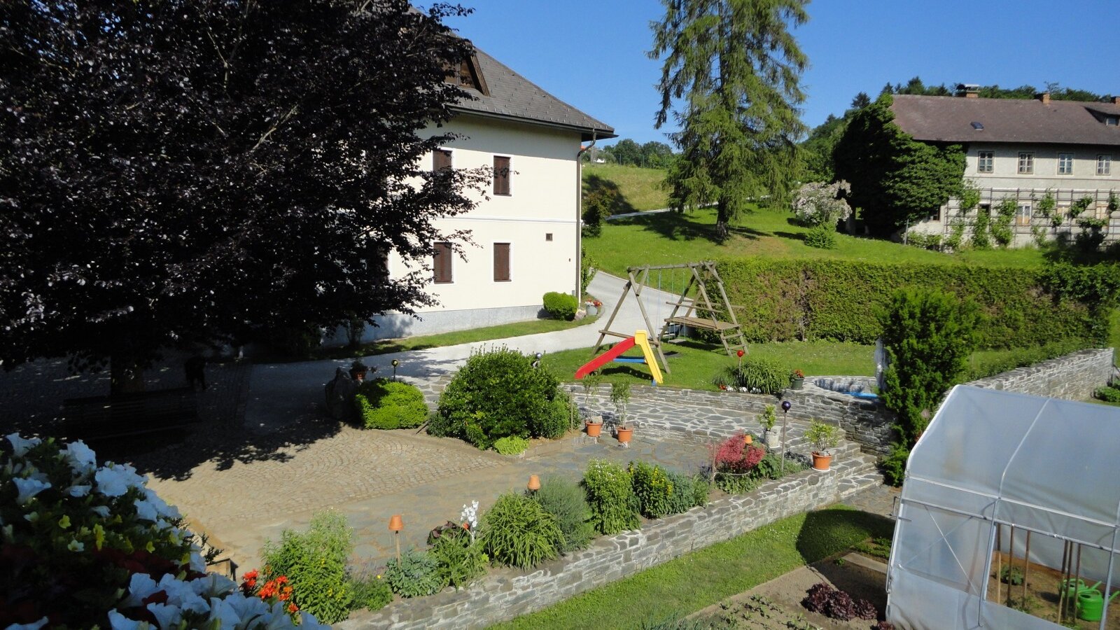 The farm house grounds feature a garden area with a children's playground and a vegetable patch with a greenhouse.